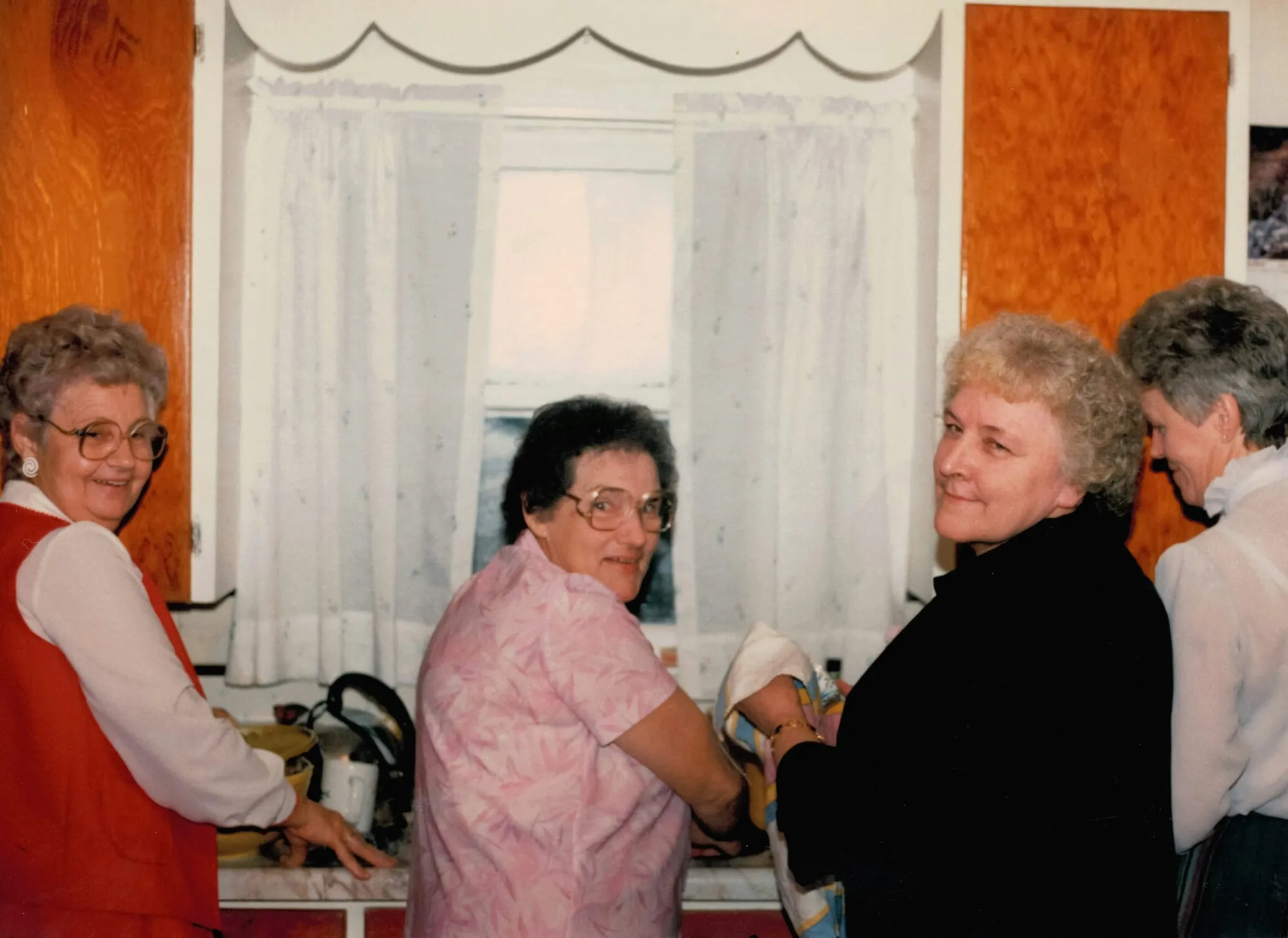 Älteres Foto: Mehrere ältere Frauen stehen lachend zusammen in einer Küche.
